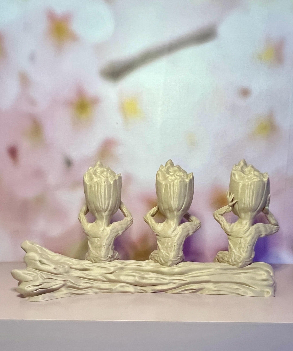 Trio de figurines beiges des trois sagesses, vue d’ensemble sur une étagère