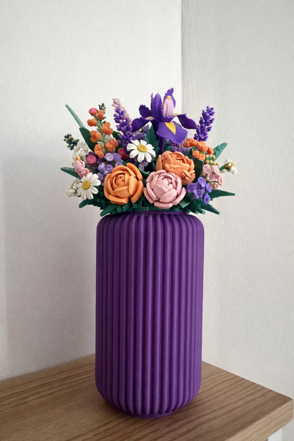Vase cannelé violet avec bouquet de fleurs LEGO® colorées sur un meuble en bois