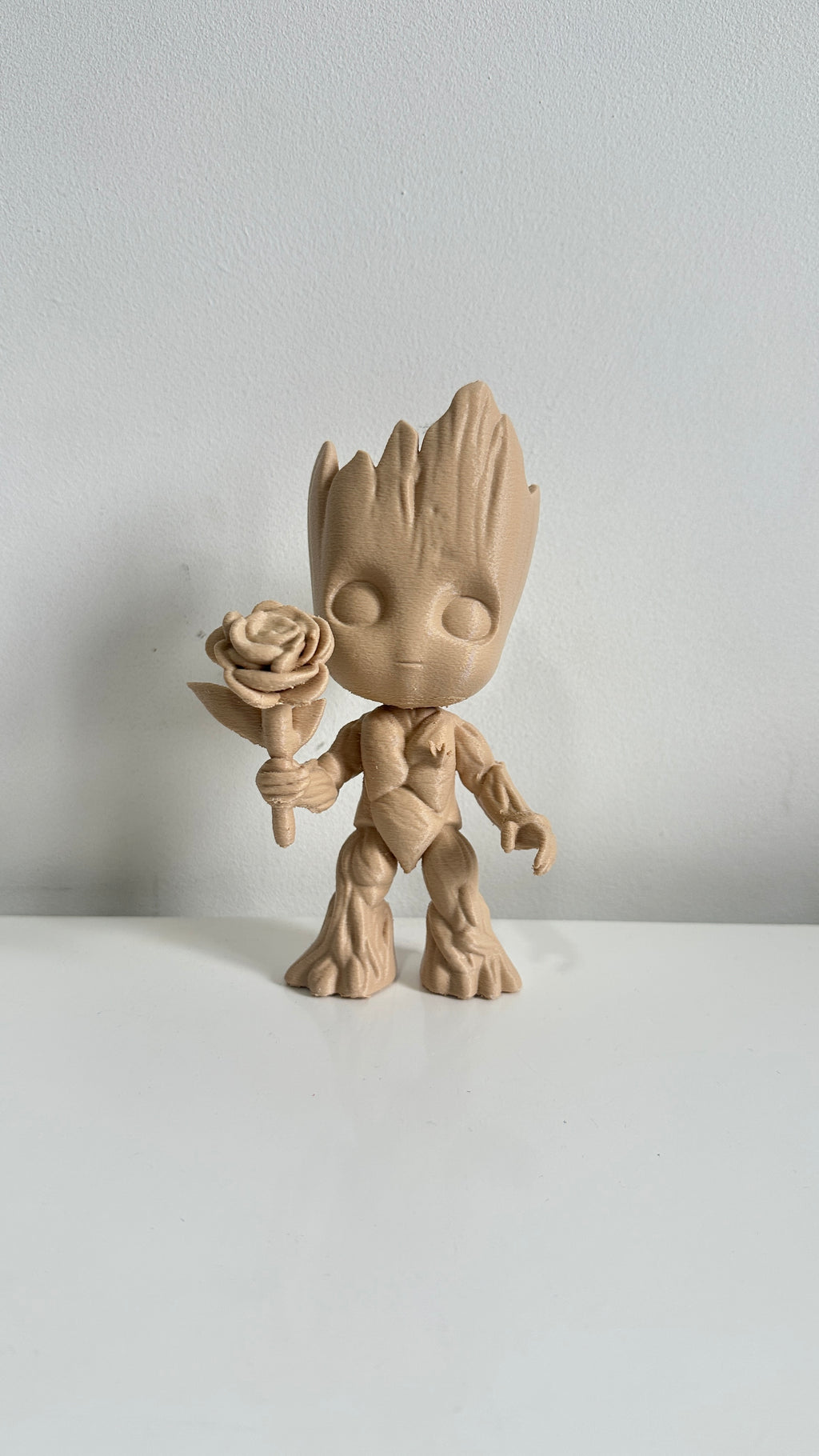 Figurine petit arbre beige tenant une fleur, vue de face