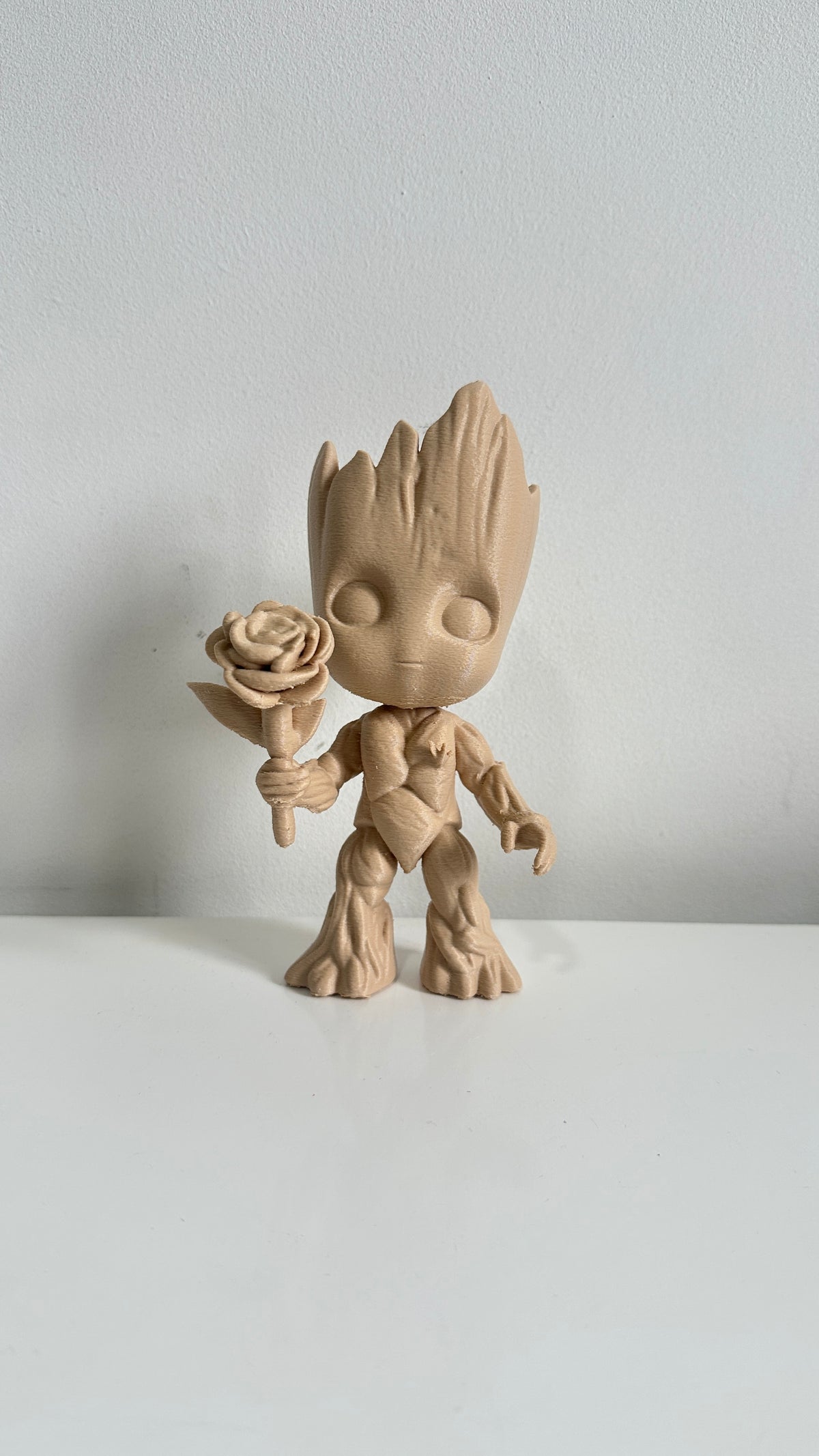 Figurine petit arbre beige tenant une fleur, vue de face