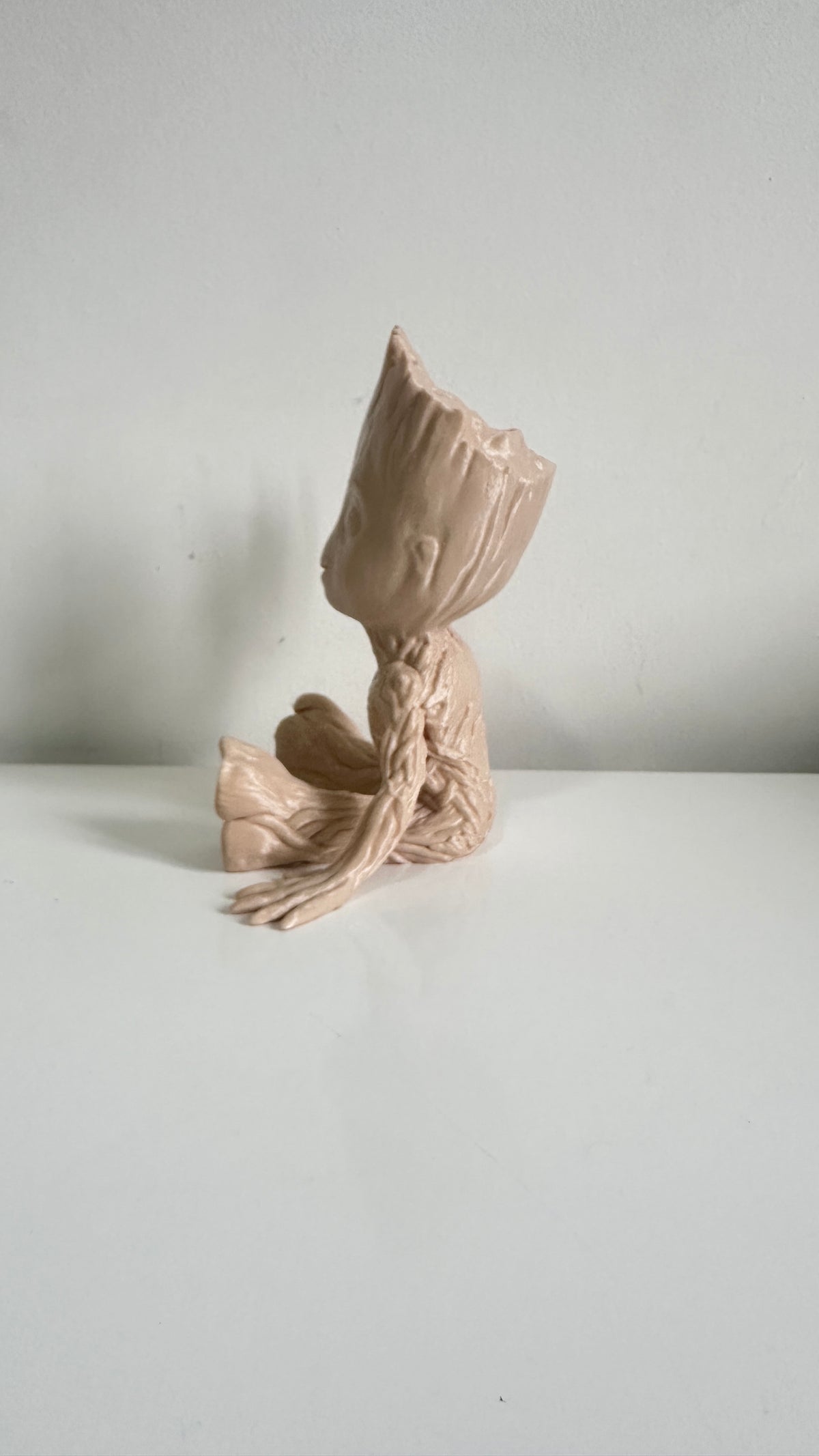 Figurine petit arbre beige bras levés, vue de dos