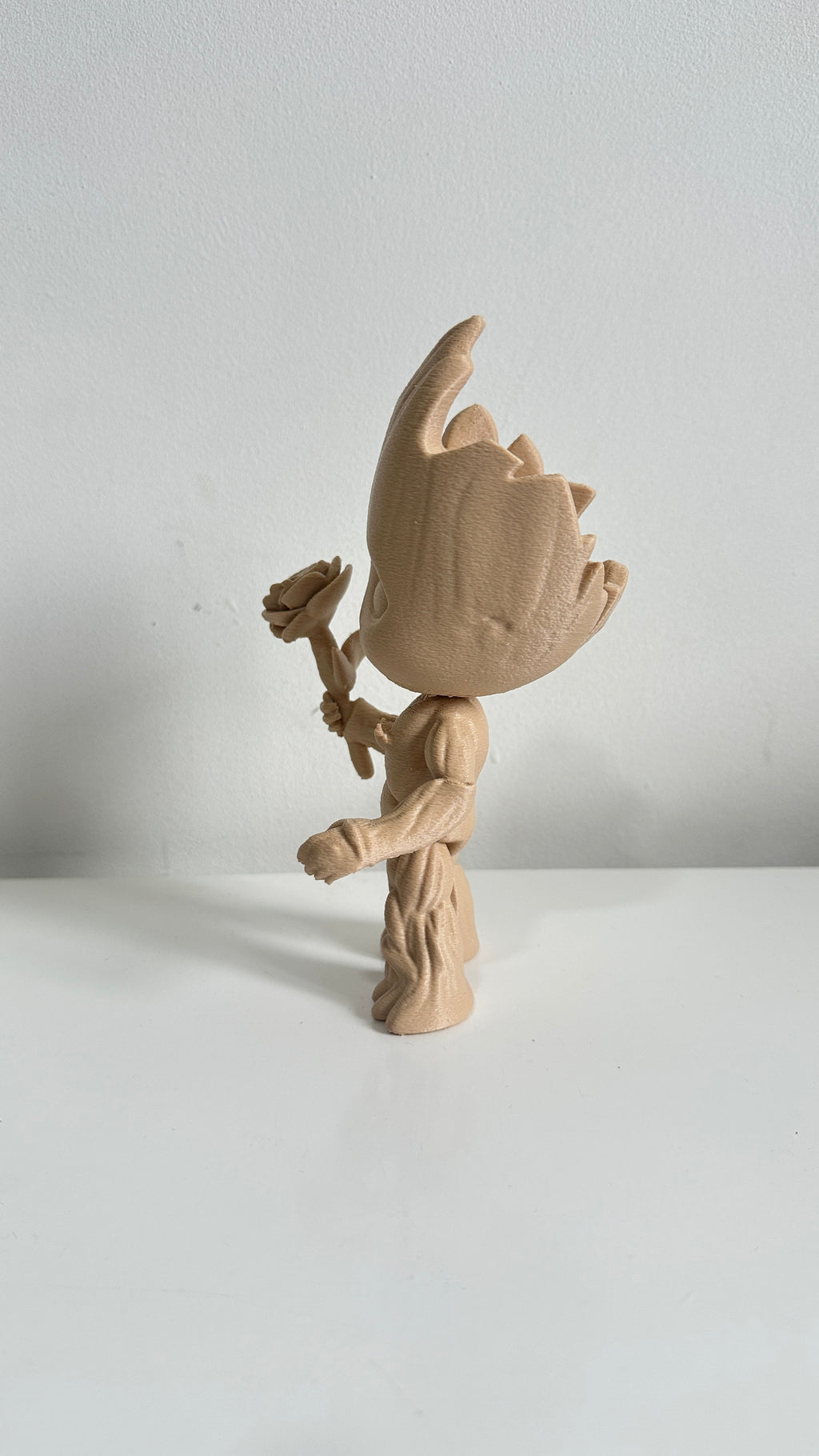Figurine petit arbre beige tenant une fleur, vue de profil