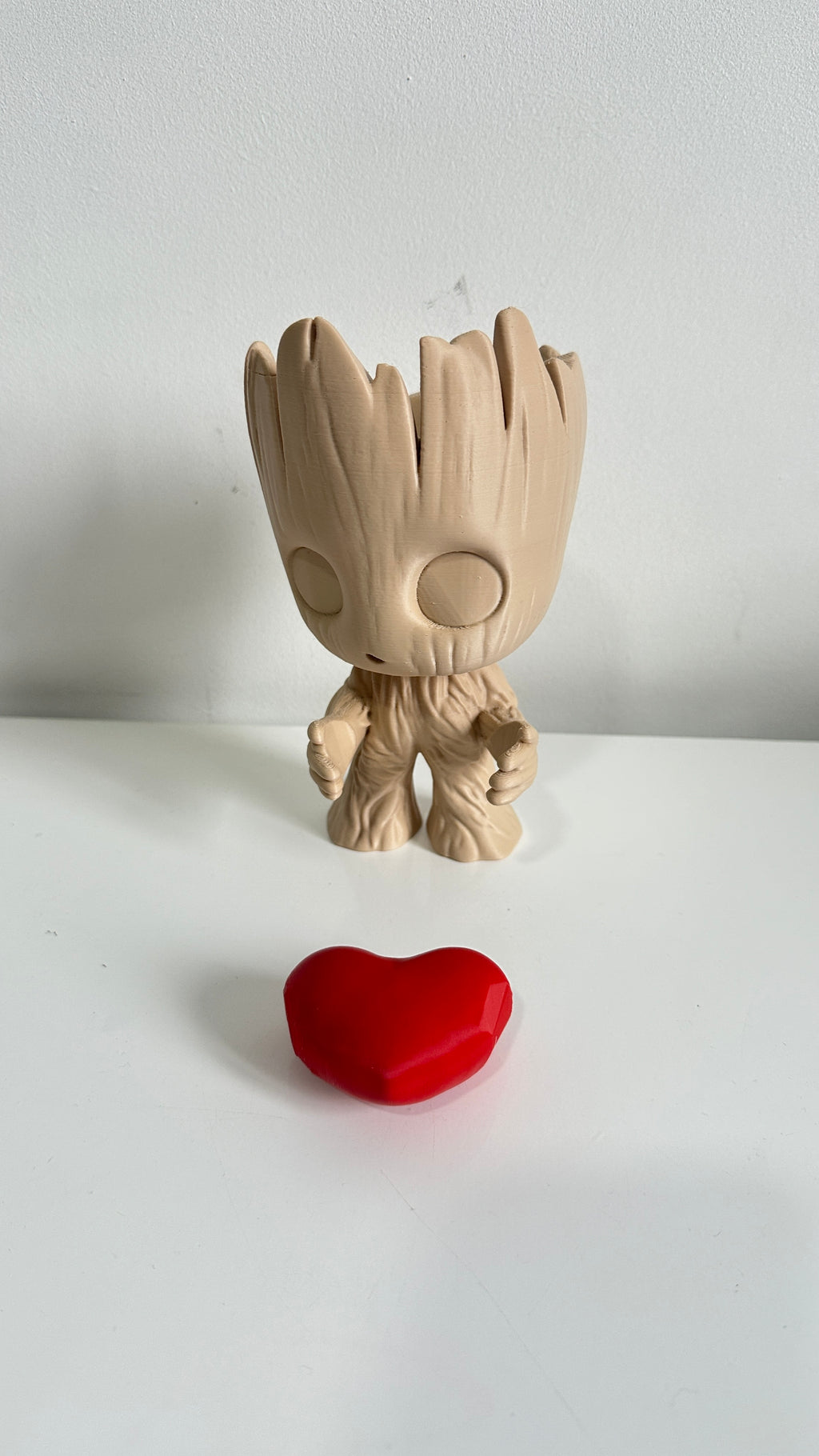 Figurine petit arbre beige tenant un cœur rouge, détail du cœur
