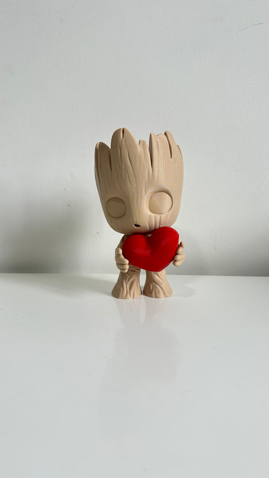 Figurine petit arbre beige tenant un cœur rouge, vue de face