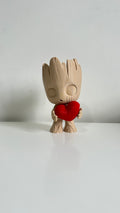 Figurine petit arbre beige tenant un cœur rouge, vue de face